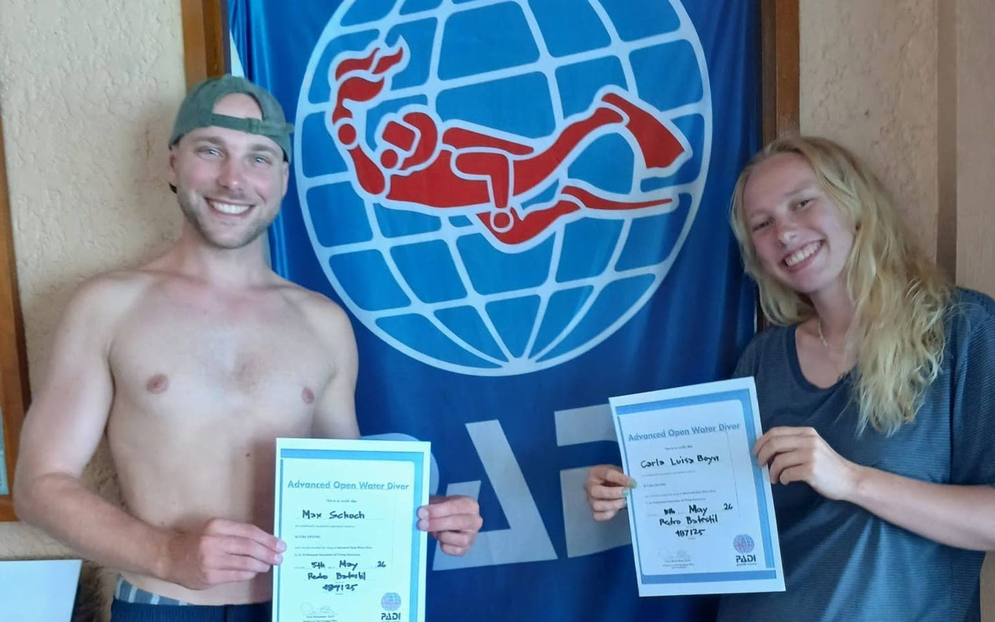 Two new PADI Advanced Open Water Divers holding their certificates
