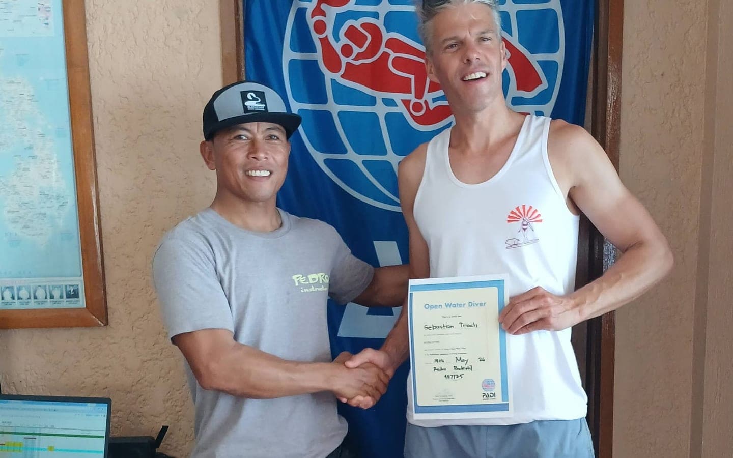 Instructor Pedro presenting a PADI Open Water Diver certificate to a student